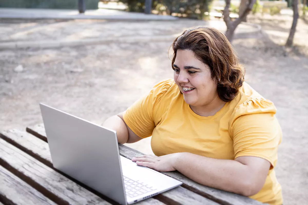 A woman smiling while looking at her laptop